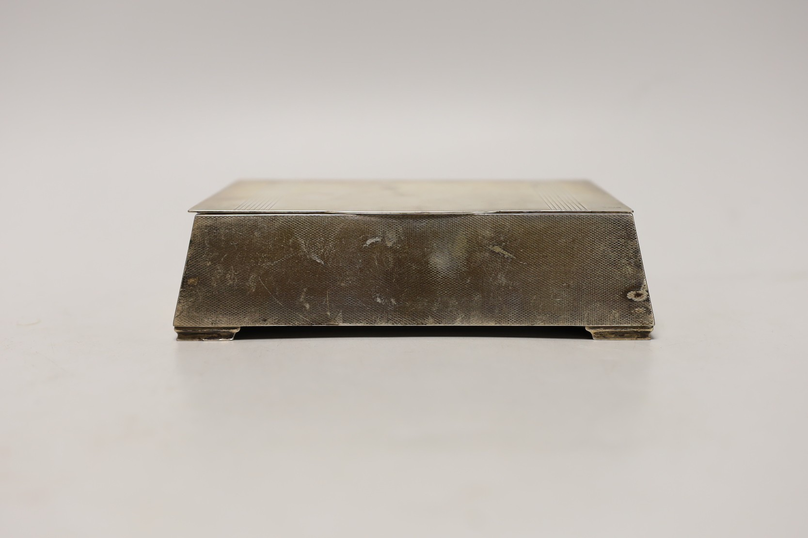 A George VI engine turned silver mounted cigarette box, of tapering rectangular form, the lid interior with engraved inscription relating to the Royal Hong Kong Golf Club, London, 1947, 17.7cm.
